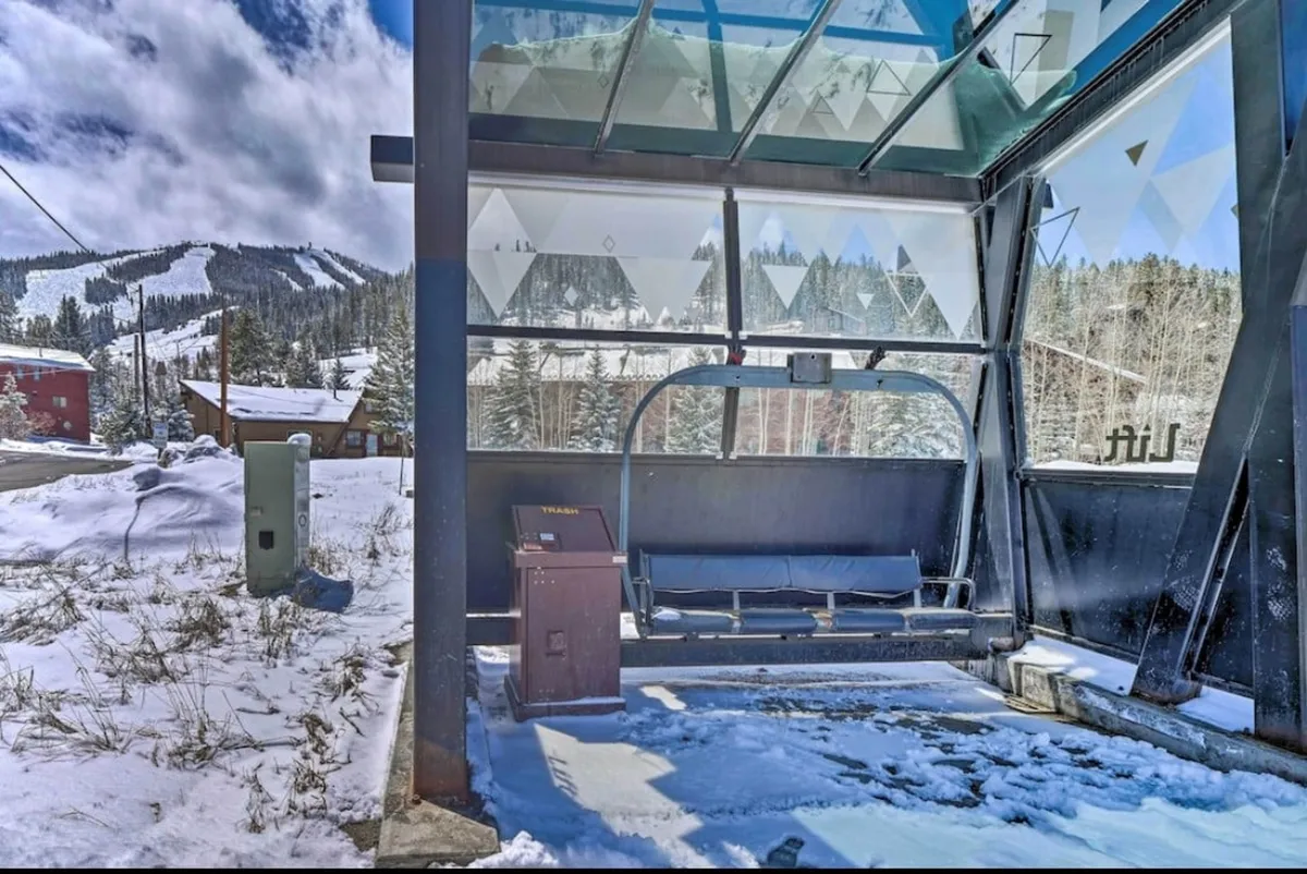 A dynamic winter scene focused on a ski lift gliding over a snow-covered landscape, with a modern glass structure in view and pristine mountains rising in the background. The area is bustling with activity, capturing the excitement and accessibility of the slopes.