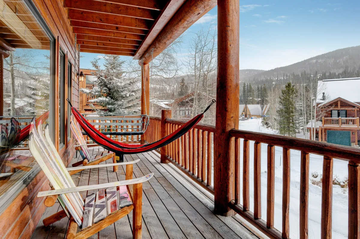 A beautiful, tranquil deck scene with a hammock, wooden railing, and snow-covered mountains in the distance. The peaceful vibe invites relaxation, reading, or quietly enjoying nature’s beauty year-round.