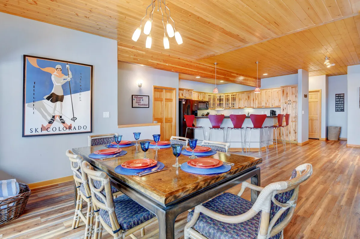 This image captures a warm, inviting dining area with a spacious table set next to the kitchen bar. The wall art and overall ambiance suggest a space perfect for group meals, family celebrations, and social gatherings. The open layout ensures the kitchen and dining areas feel connected, allowing the chef to remain part of the action.